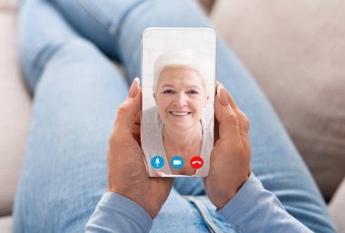 Bir kadın akıllı telefon kullanarak büyükannesiyle görüntülü konuşma yapıyor.