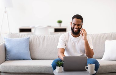 Bilgisayarda çalışan Afrikalı adamın evde telefon görüşmesi var.