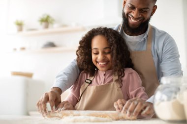 Mutlu siyah adam ve kızı hamuru yuvarlıyor