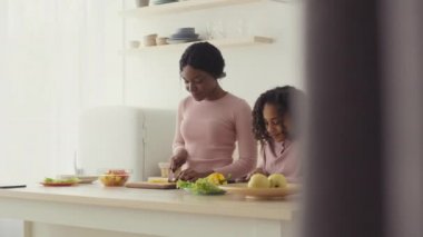 Annemin yardımcısı. Afrika kökenli Amerikalı anne, mutfakta kızıyla yemek hazırlıyor, birbirlerine gülümsüyor, çekim takibi yapıyor.