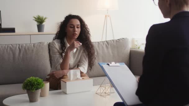 Konsultacja psychologiczna. Przygnębiona kobieta z serwetką rozmawiająca z psychoterapeutą podczas osobistego spotkania — Wideo stockowe