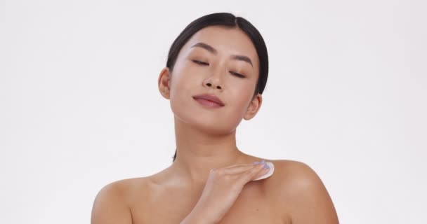 Joven mujer asiática hidratando su piel decollete área con loción de mimos, fondo blanco estudio, cámara lenta — Vídeos de Stock
