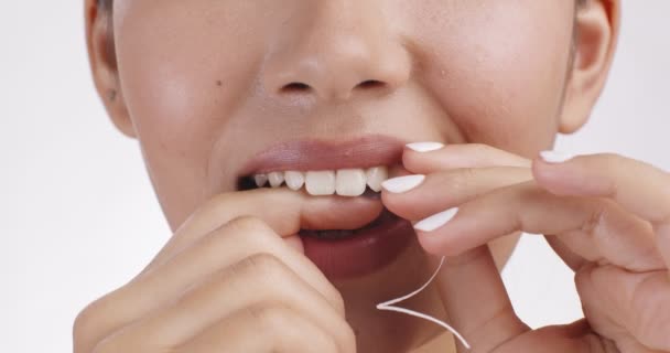 Оральный уход. Крупный план молодой женщины, чистящей зубы зубной нитью, белый студийный фон, замедленная съемка — стоковое видео