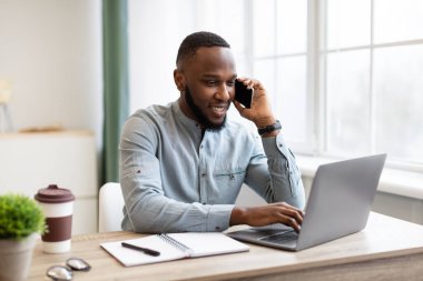 Mutlu Afrikalı İş Adamı Cep telefonuyla konuşuyor İş yerinde oturuyor