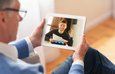 Adam akıllı telefon kullanarak oğluyla görüntülü görüşme yapıyor.