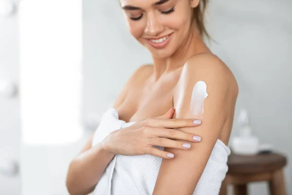 Жінка застосовує зволожуючий лосьйон на плечах догляд за шкірою в приміщенні — стокове фото