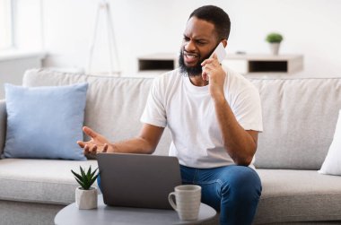 Siyah adam telefonda konuşuyor. İçerideki bilgisayarla ilgili bir sorun var.