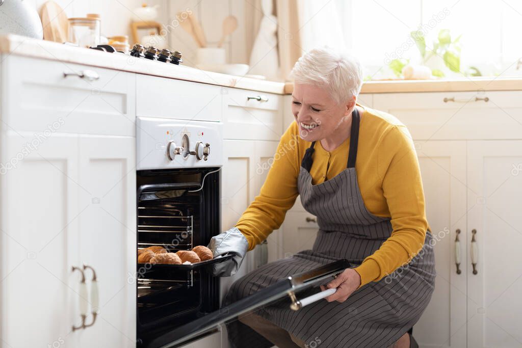 Happy Matured Woman Opening Oven at Kitchen