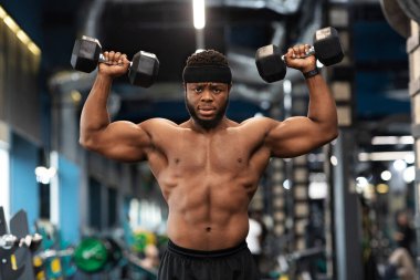 Motive olmuş Afro-Amerikan vücut geliştirici pazılar ve ağırlık egzersizleri üzerinde çalışıyor.