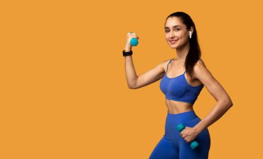 Turuncu Arkaplanda Dambıllarla Egzersiz Yapan Kadın