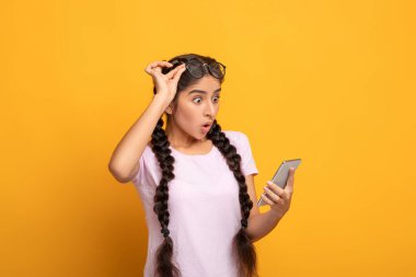 Cep telefonu kullanan heyecanlı Hintli kadın, online zaferi kutluyor.