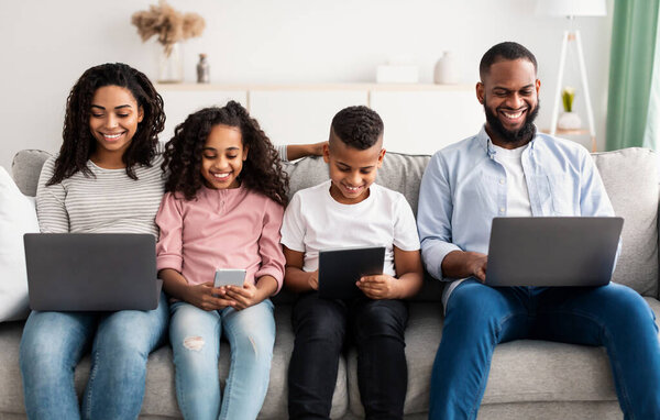 Happy african american family holding and using gadgets