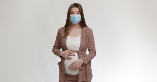 個人の保護と安全。若いです妊娠中の女性身に着けています保護医療面マスクストローク彼女の大きな腹 — ストック動画