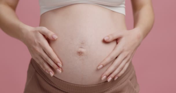 As mães puras amam. Close up de mulher grávida abraçando sua barriga grande, fundo de estúdio rosa, câmera lenta — Vídeo de Stock