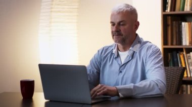 Emekliliğe. Yorgun, olgun bir adam yorgun gözlerini ovuşturuyor, ofisteki dizüstü bilgisayarda çalışıyor.
