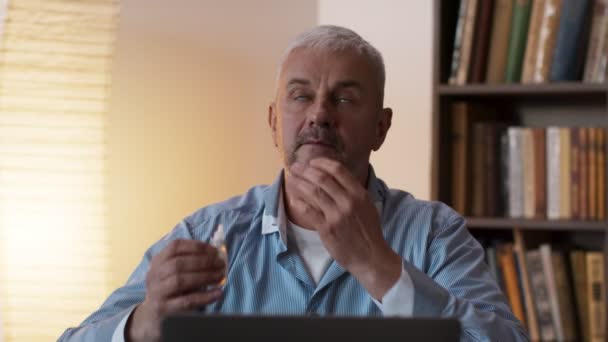 Curar a visão. Homem de meia idade deixando cair os olhos com colírio antes do trabalho no computador, sentado no escritório em casa — Vídeo de Stock