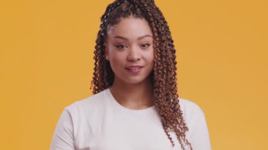 Sevimli Afro-Amerikalı kadın başparmağını kaldırıyor ve kameraya gülümsüyor, turuncu arka plan, yavaş çekim