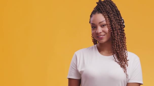 젊고 아름다운 아프리카 계 미국인 여성 이 카메라 앞에서 웃으며 빈 공간 과 주황색 배경 위에 서 있는 모습 — 비디오