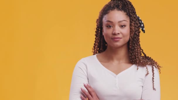 Mulher americana africana confiante sorrindo para a câmera com os braços dobrados, posando sobre fundo laranja com espaço livre — Vídeo de Stock