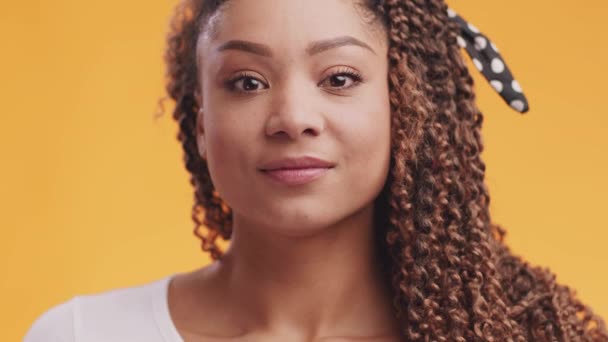 Gros plan portrait de jeune femme afro-américaine reconnaissante touchant sa poitrine avec gratitude, fond orange — Video