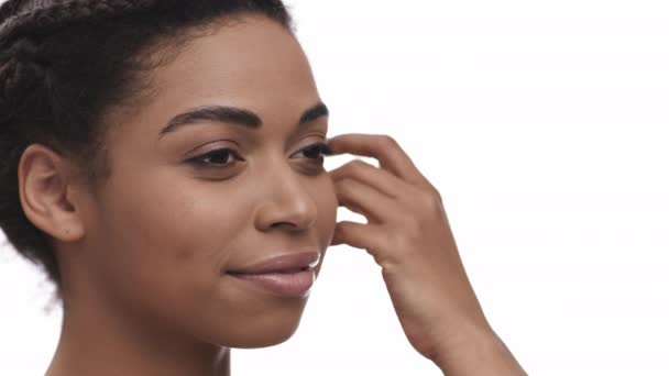 Piękny portret młodej Afroamerykanki cieszącej się gładką skórą policzka, białym tłem pracowni, pustą przestrzenią — Wideo stockowe