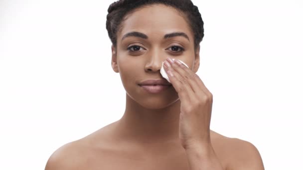 Make-up verwijderen. Jonge mooie zwarte dame schoonmaken van haar gezicht met katoen pad, hydraterende haar huid, glimlachen naar de camera — Stockvideo