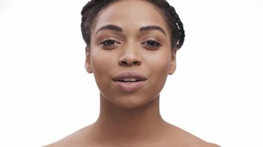 Güzel Afrikalı Amerikalı kadın kameraya öpücük yolluyor ve gülümsüyor, beyaz arka plan, yavaş çekim