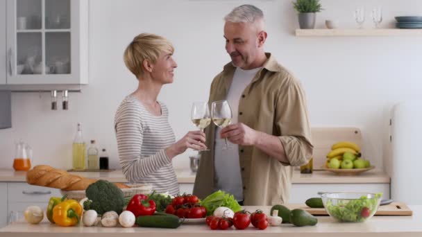 Małżonkowie Clinking okulary Picie wina Przygotowanie kolacji razem w kuchni — Wideo stockowe