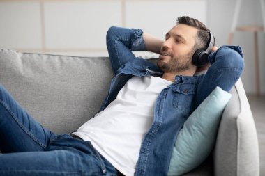 Kulaklıklı yakışıklı sakallı adam müzik dinliyor.