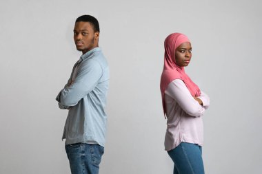 Gri renkte sırt sırta duran üzgün siyah çift