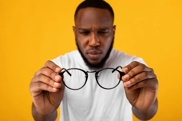 Man Holding Eyeglasses Squinting Eyes Having Poor Eyesight, Yellow Background