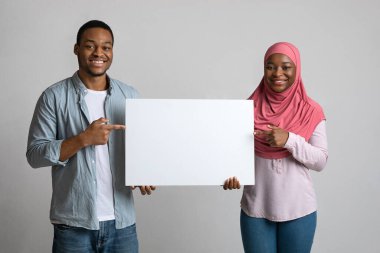 Neşeli siyah çift boş pankartı işaret ediyor.