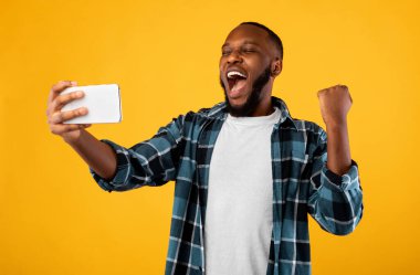 Siyah adam telefonu tutuyor ve sarı arka planda 