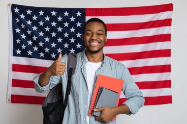 Amerikan bayrağının başında dikilen neşeli siyahi adam başparmağını kaldırıyor.