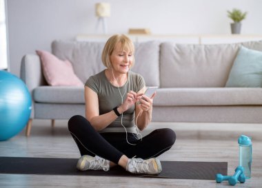 Akıllı telefondan online spor videosu izleyen güzel bir kadın. Antrenmandan sonra ara veriyor, yer kopyalıyor.