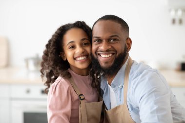Neşeli siyah baba ve kızı mutfakta poz veriyor.