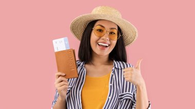 Asyalı bir kadın pasaportunu elinde tutuyor.