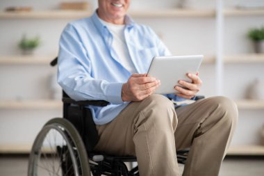 Tekerlekli sandalyedeki engelli yaşlı adamın evde online iletişim için tablet bilgisayar kullanması görüntüsü