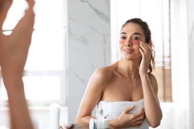 Woman Applying Under-Eye Patches Moisturizing Skin Under Eyes In Bathroom clipart