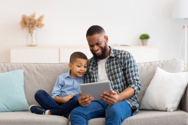 Siyah Baba ve Oğlu Evde Otururken Dijital Tablet Kullanıyor