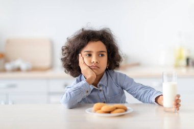 Elinde bir bardak süt tutan üzgün afro kızın portresi.