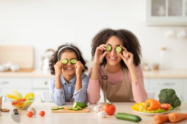 Siyah anne ve kızı mutfakta yemekle oynuyorlar.