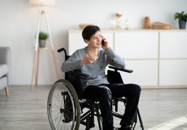 Tekerlekli sandalyedeki neşeli genç arkadaşlarıyla telefonda konuşuyor.