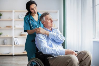 Genç doktor engelli erkeklerin elini tutuyor, huzurevinde ona destek oluyor.