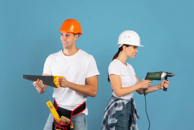 Tamirat sırasında inşaat aletleriyle eğlenen şapkalı genç çift.