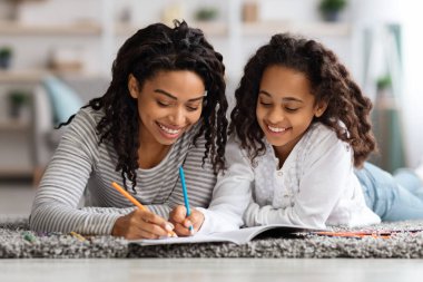 Neşeli anne ve kız evde birlikte çiziyorlar.