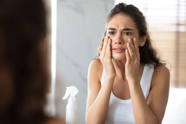 Donna infelice guardando rughe toccare la pelle del viso in bagno — Foto Stock