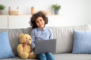 Kanepede oturan ve dizüstü bilgisayarını kullanan kız.