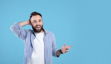 Mutlu genç adam boşluğu işaret ediyor, mavi stüdyo arka planında büyük bir satış yaptığı için şansına inanamıyor, afiş tasarımı