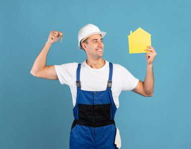 Kapaktaki mutlu tamirci, sıkı şapkalı anahtar ve kağıt ev figürü.